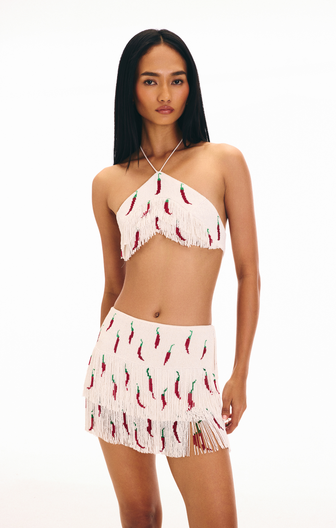 Woman wearing a two-piece outfit with chili pepper pattern on white beaded tassels