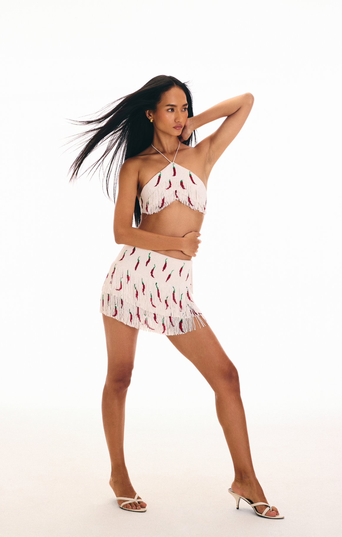 Woman wearing a two-piece outfit with chili pepper pattern on white beaded tassels